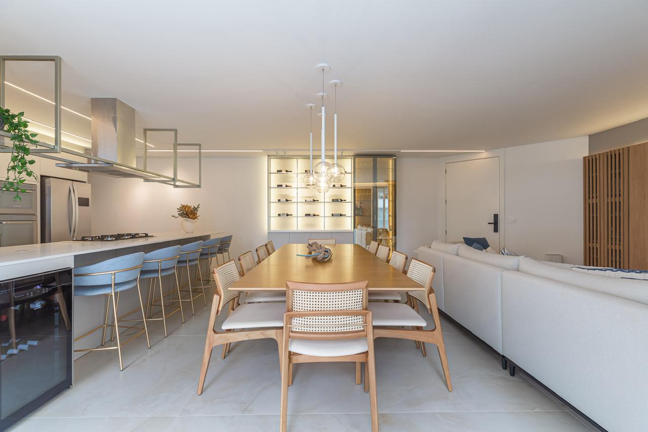 Sala de jantar integrada com cozinha, ilha gourmet, mesa em madeira e iluminação elegante